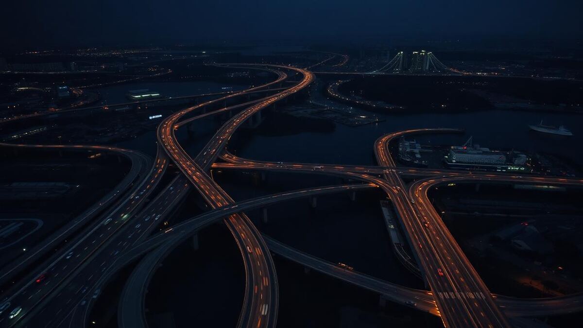 Aerial night view of an interconnected motorway and port with orange light trails